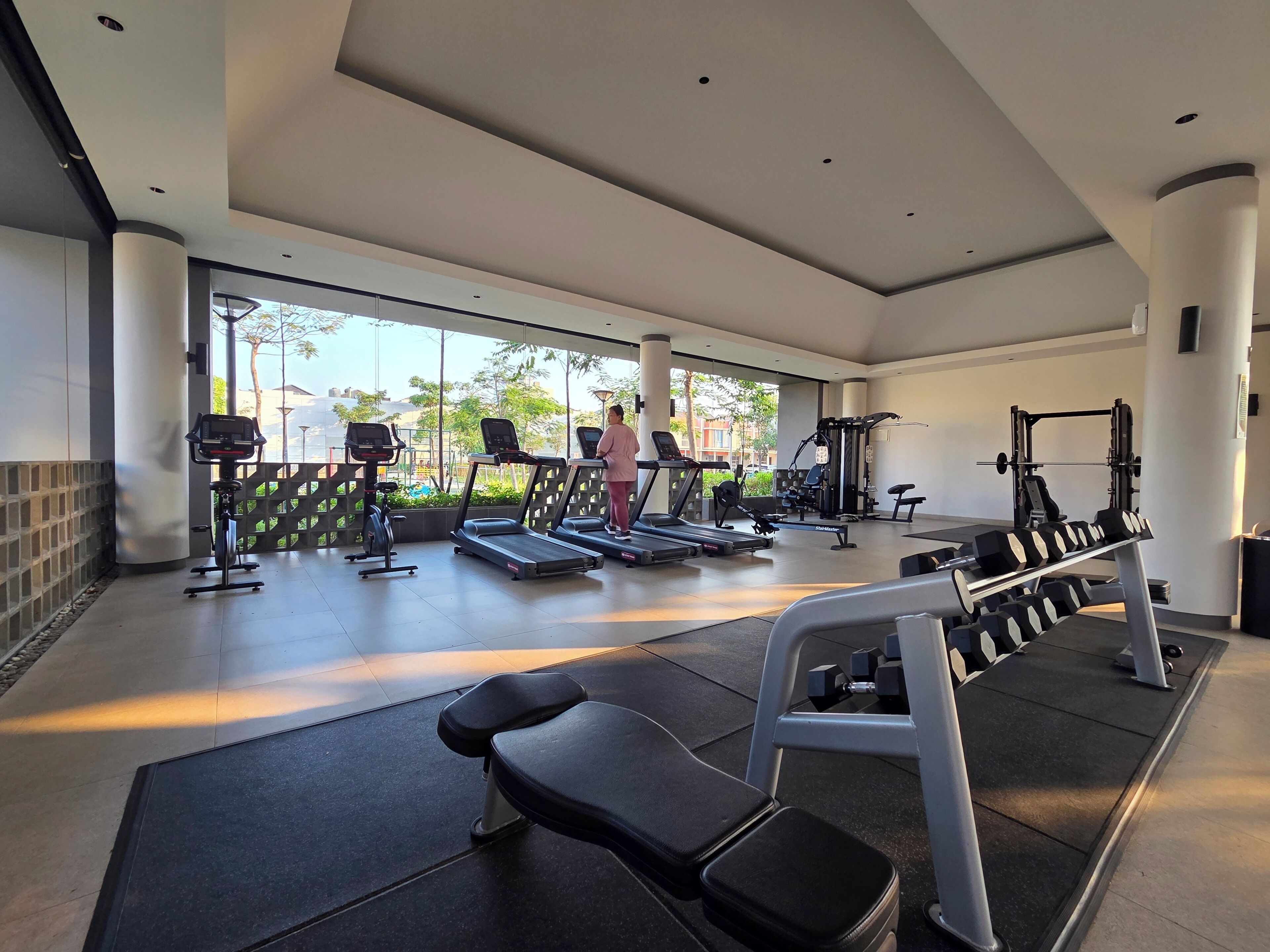 Un gimnasio con cintas de correr, máquinas de pesas y bancos.