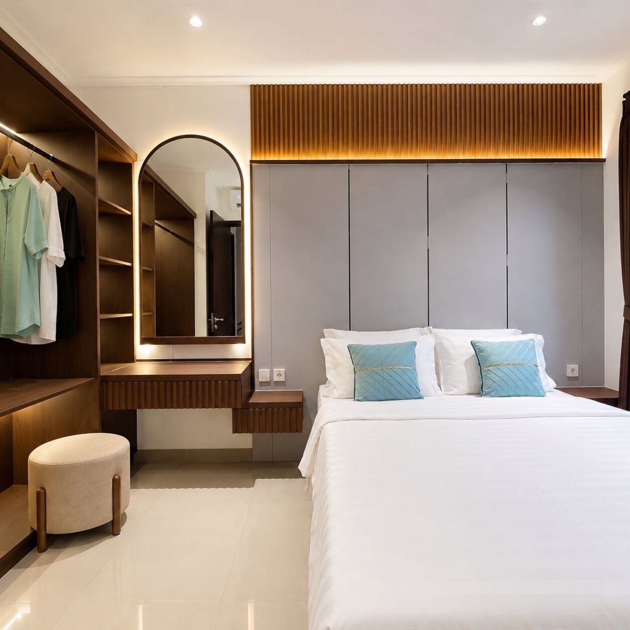 A modern bedroom with a large bed, a built-in wardrobe, a vanity with a mirror, and a round ottoman.