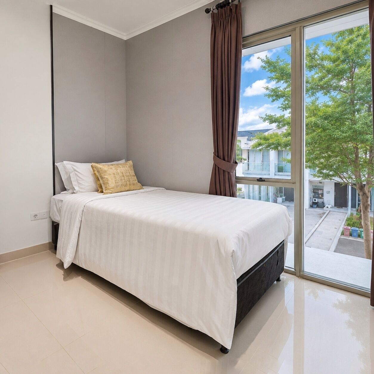 Un dormitorio moderno con una cama, un ventanal con cortinas y vistas al exterior.