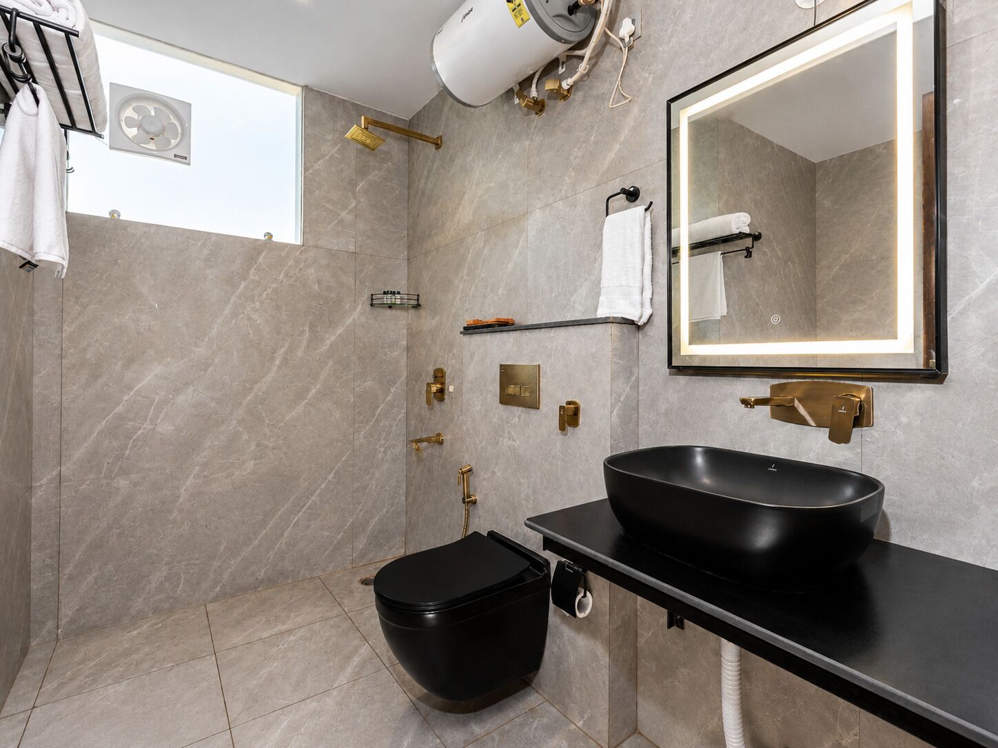 Un baño moderno con un lavabo negro, un espejo, toallero y zona de ducha.