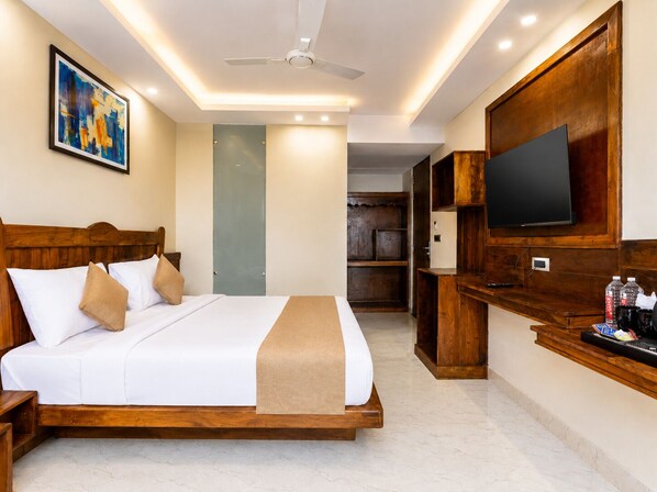 A hotel room with a bed, a television, a wardrobe, and a ceiling fan.