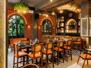 A restaurant interior with brick walls, arched windows, and a bar area with shelves of bottles.