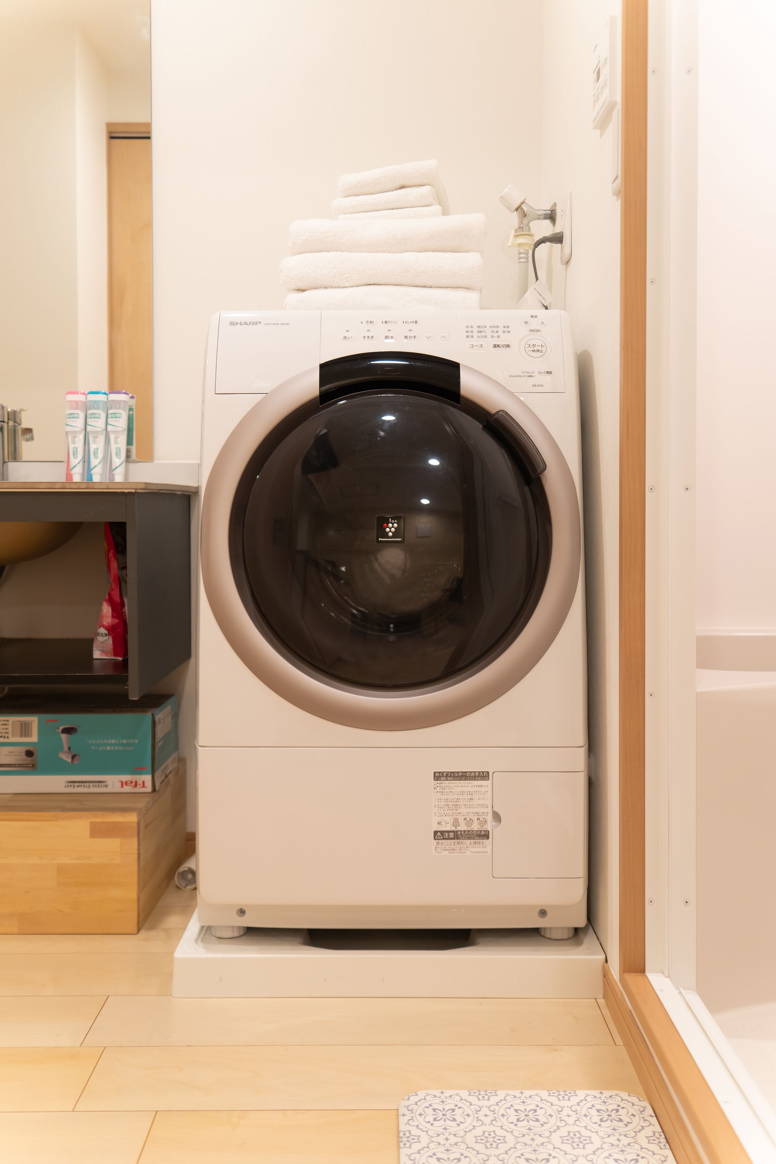 A front-loading washing machine in a room with a wooden floor and a white wall.
