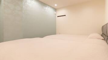 A bedroom with a bed, a wall-mounted shelf, and a ceiling light.
