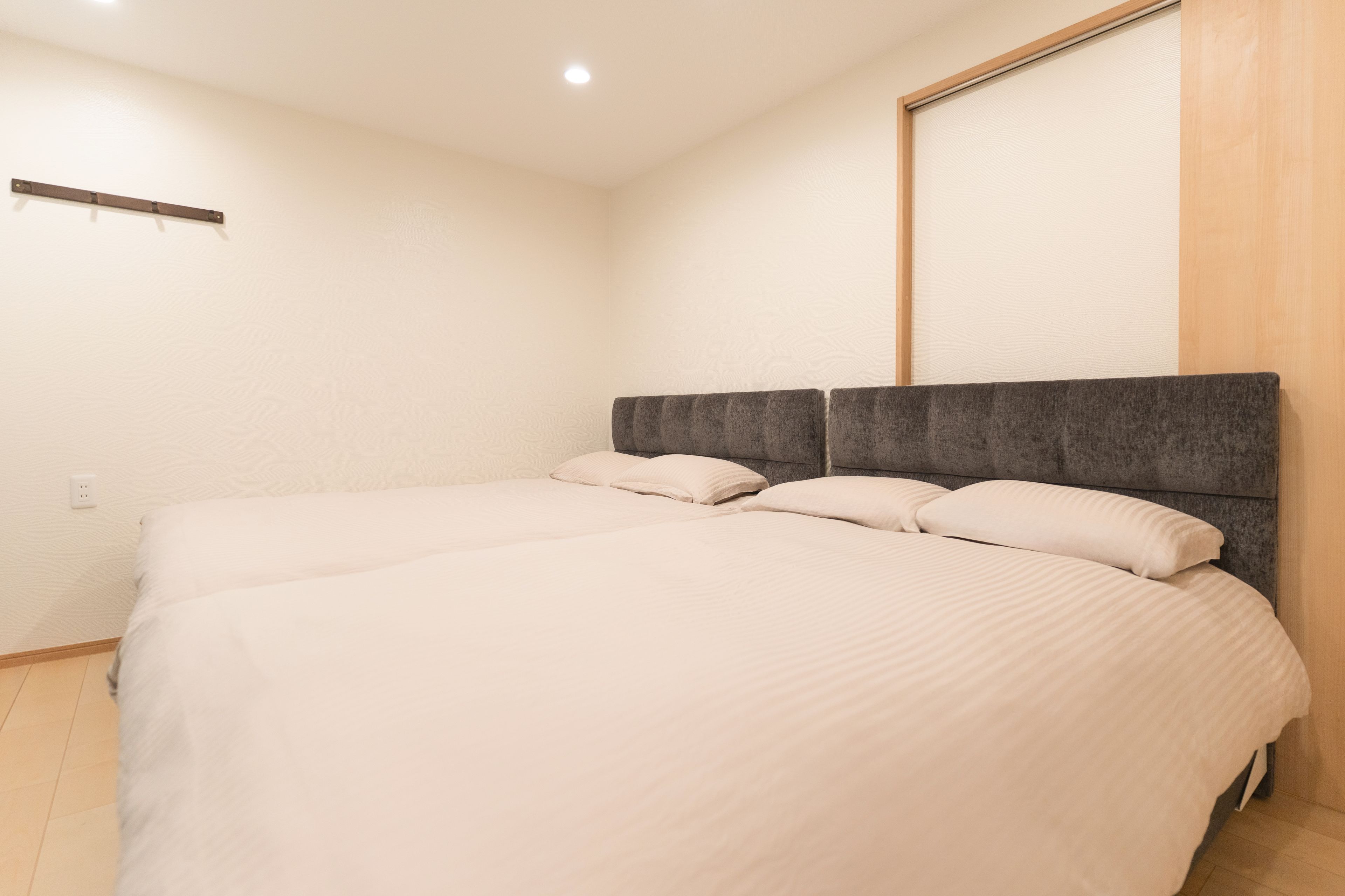 A hotel room with two beds, a wooden headboard, and a large window.