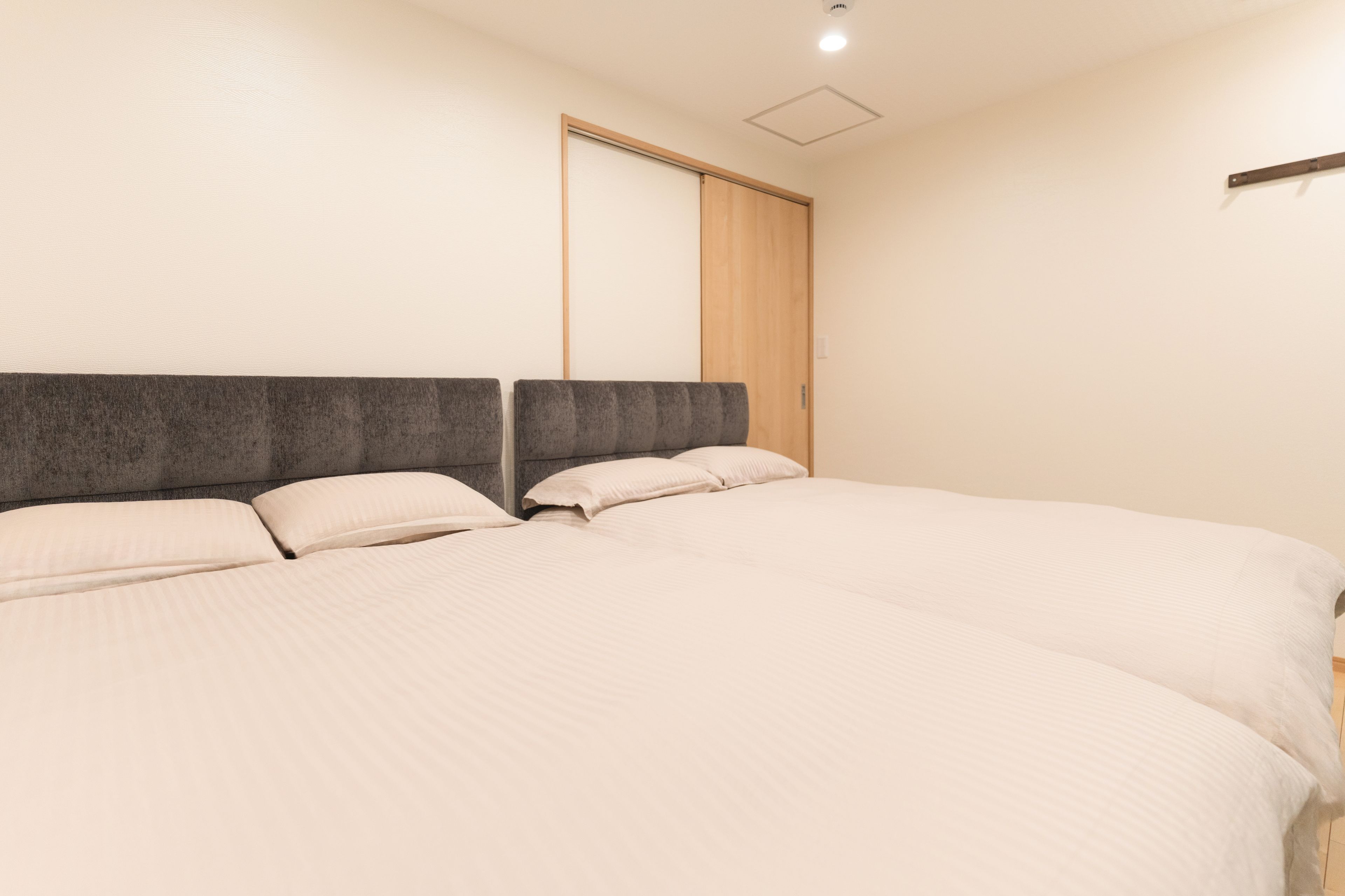A bedroom with a large bed, a headboard, and a wooden closet door.