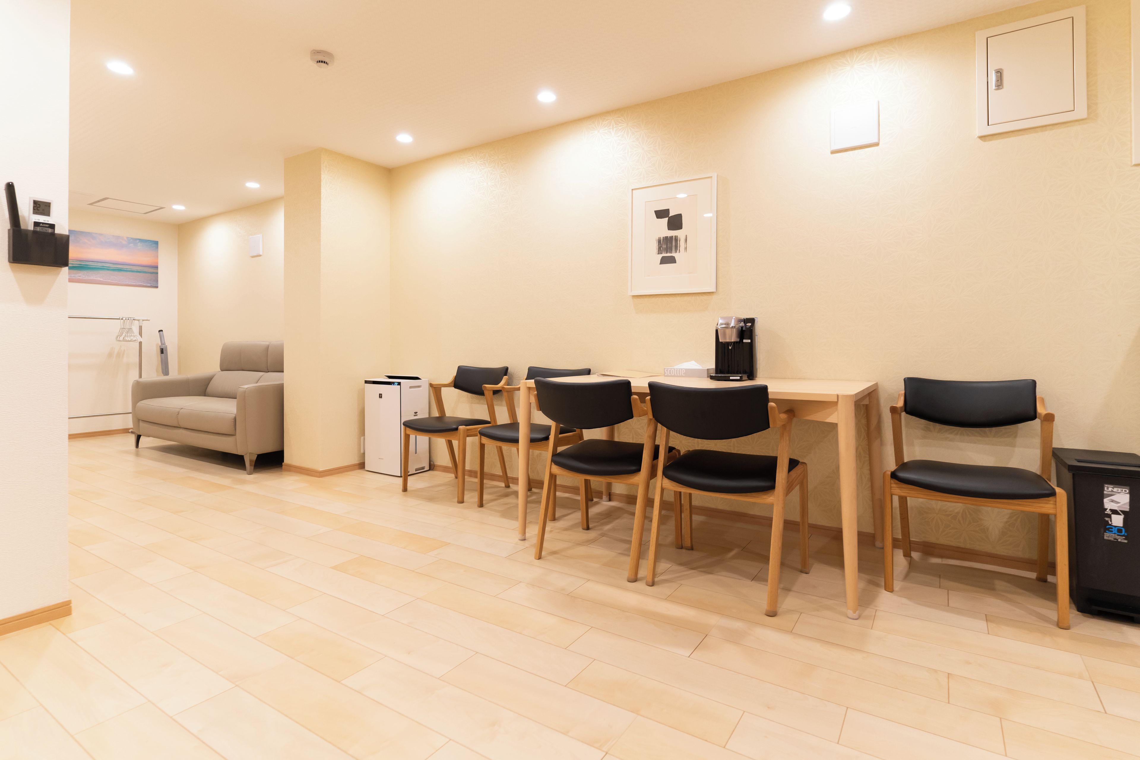 A dining area with a table, chairs, a sofa, a coffee machine, and a refrigerator.