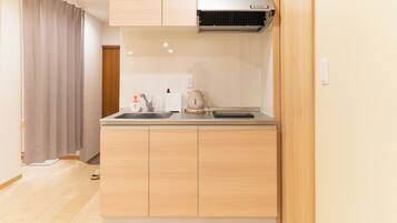 A compact kitchen with a built-in stove, a sink, and a coffee maker.