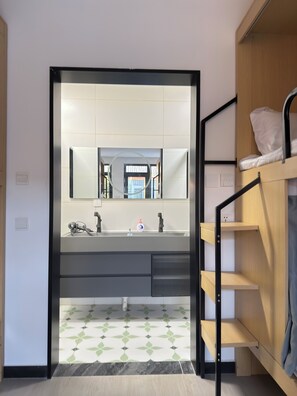 Une salle de bain moderne avec un grand miroir, un lavabo et un espace douche.