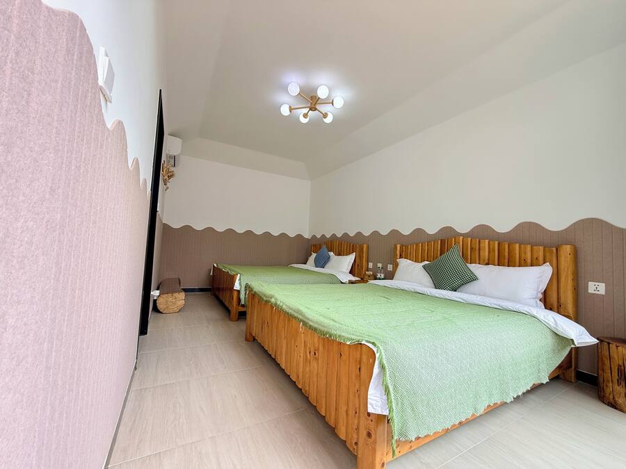 Una habitación con dos camas de madera, una lámpara en el techo y un aire acondicionado instalado en la pared.