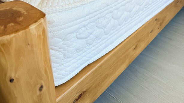 A wooden bed frame with a mattress and pillows.
