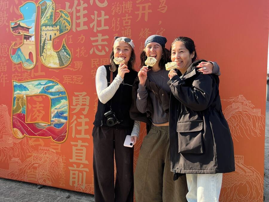 Un grupo de personas frente a un muro con grandes caracteres e ilustraciones chinas.