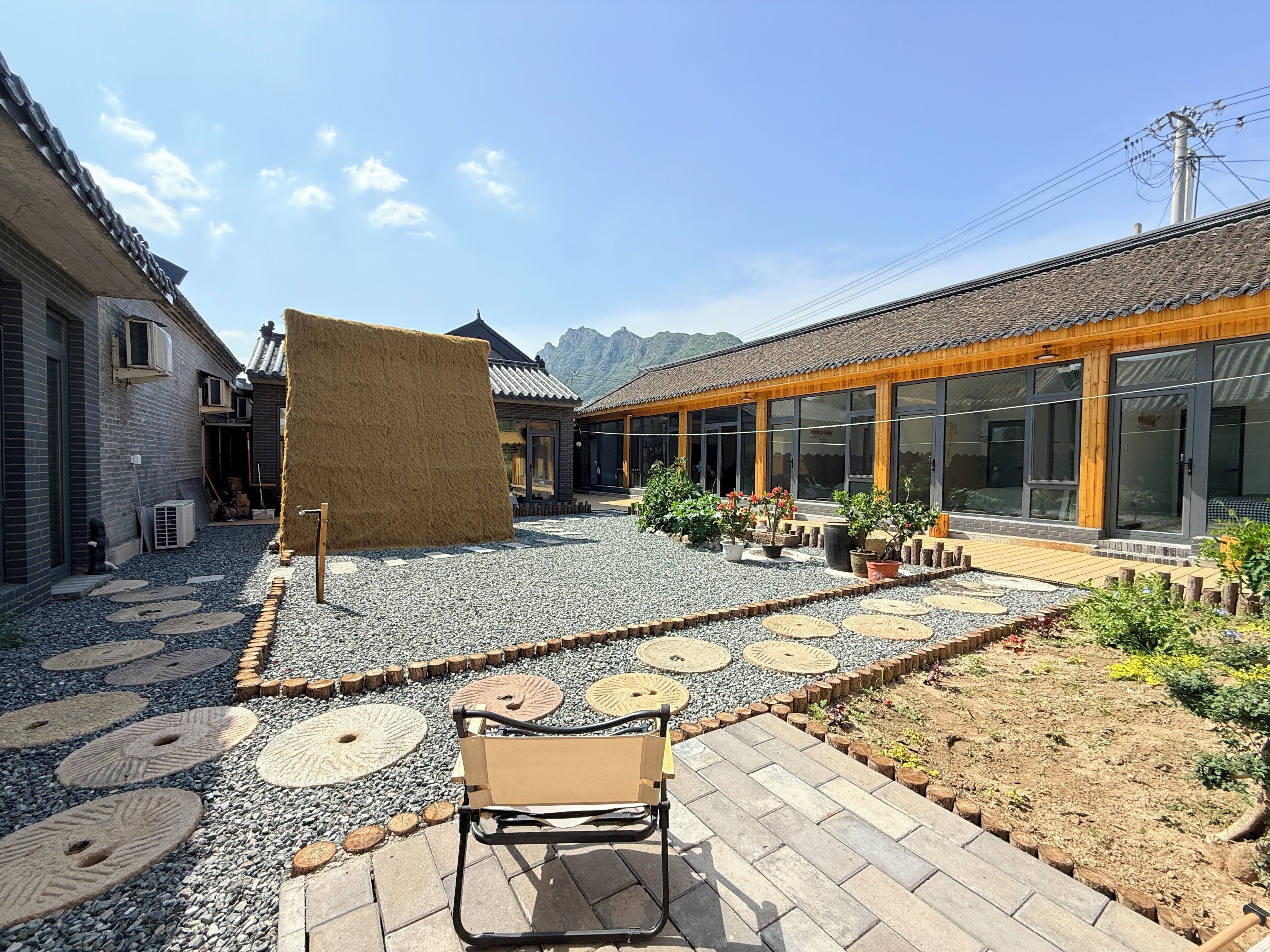 A courtyard with a traditional building, a modern structure with large windows, and a wooden bench.