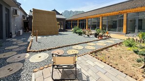 A courtyard with a traditional building, a modern structure with large windows, and a wooden bench.