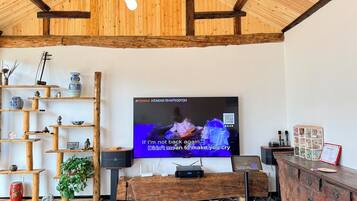 A room with a wooden ceiling, a television mounted on the wall, and a wooden cabinet with drawers.