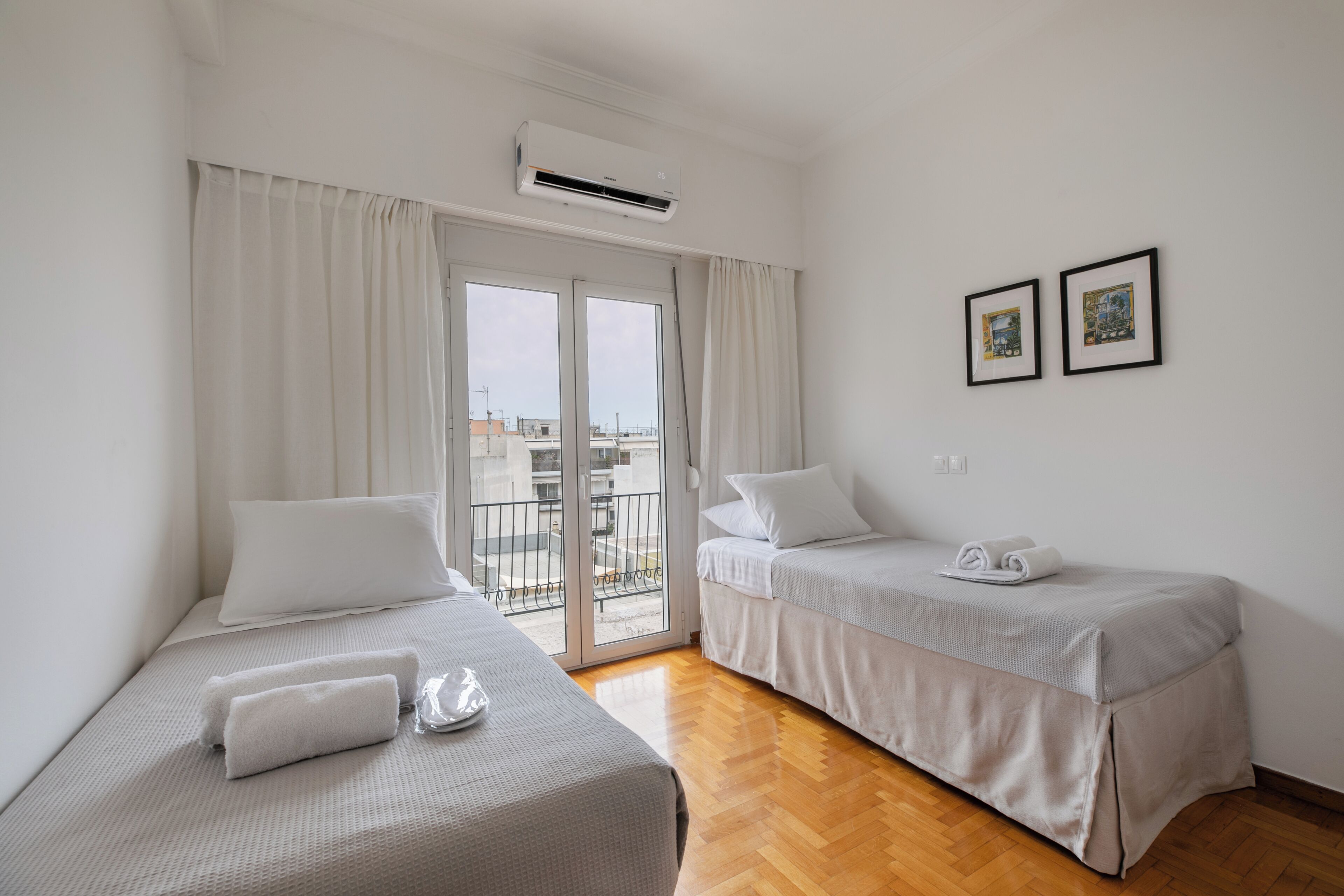 Habitación de hotel con dos camas, un balcón y vistas a la ciudad.
