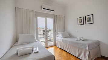 Ein Hotelzimmer mit zwei Betten, einem Balkon und Blick auf die Stadt.
