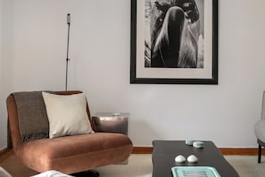 Una sala de estar con un sofá marrón, una mesita auxiliar y una fotografía en blanco y negro enmarcada en la pared.