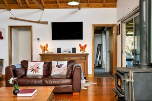 Ein gemütliches Wohnzimmer mit Ledersofa, Flachbildfernseher, Kamin und Holzschrank.