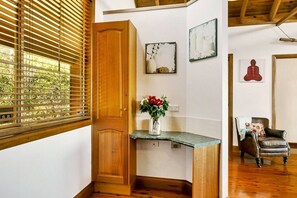 Ein Zimmer mit Holztür, einem kleinen Tisch mit Blumenvase und einem Stuhl.