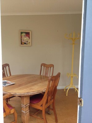 Ein Esszimmer mit Holztisch und Stühlen, einem Gemälde an der Wand und einem gelben Beistelltisch.