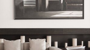 Una sala de estar moderna con un sofá, una silla y una obra de arte grande enmarcada en la pared.