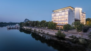 Ein modernes Hotel mit Blick auf das Wasser, inklusive einem Spiegelbecken und einem Bootssteg.