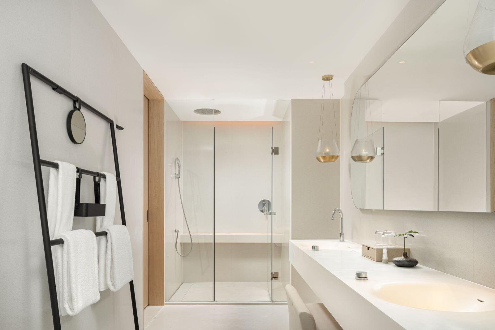 A modern bathroom with a glass shower enclosure, a large mirror, and a white sink.