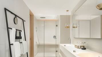 A modern bathroom with a glass shower enclosure, a large mirror, and a white sink.
