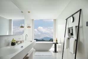 Un bany modern amb una banyera gran, un lavabo doble i una finestra gran que ofereix vista a les muntanyes.