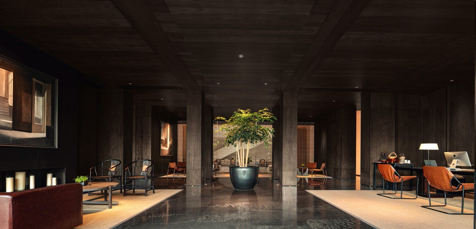 Un moderno vestíbulo de hotel con una planta central, zonas de estar y un mostrador de recepción.