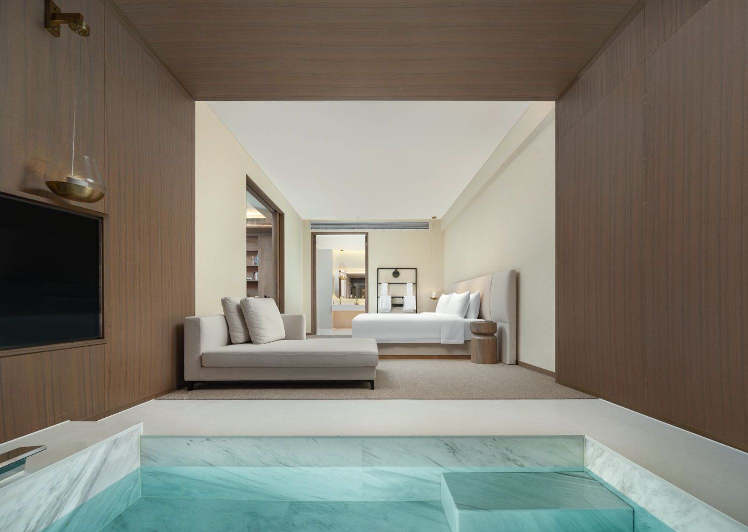 Een moderne hotelkamer met een groot bed, een slaapbank, een klein tafeltje en een ingebouwd whirlpool.