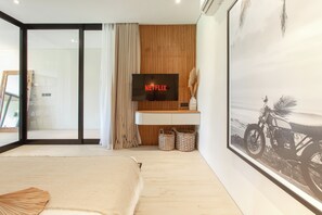 Een moderne slaapkamer met een groot bed, een wandgemonteerde televisie waarop 'NETFLIX' wordt weergegeven, en een lijst met een foto van een motor.