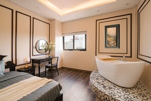 Ein Schlafzimmer mit Bett, Schreibtisch, Stuhl, einer großen Badewanne und einem Fenster.