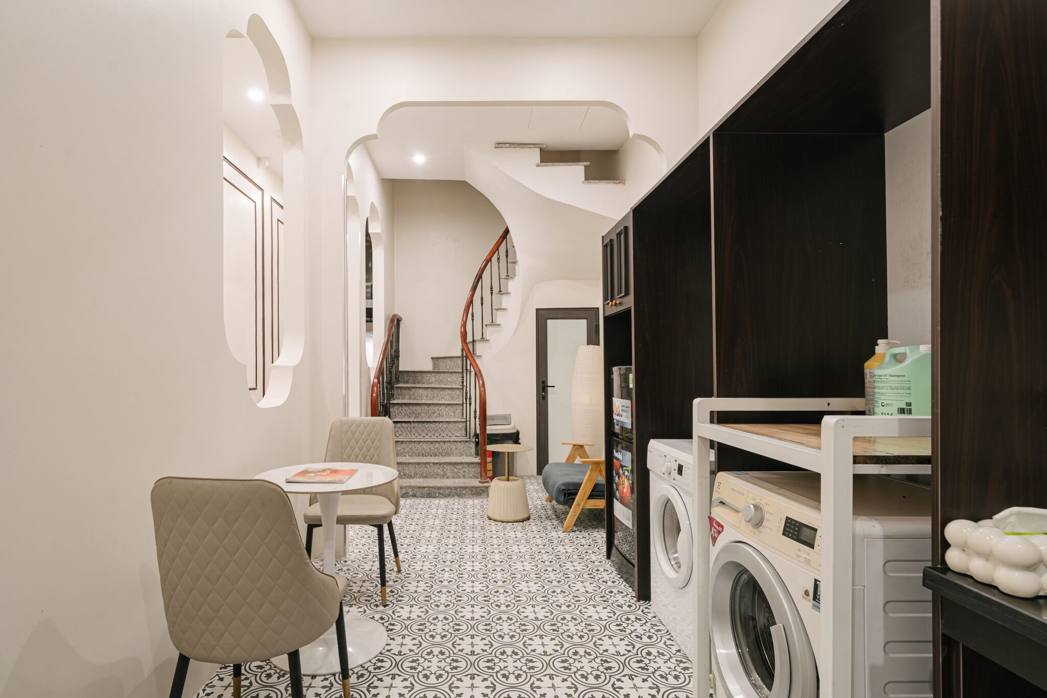 A laundry room with a washing machine, dryer, and shelves with laundry supplies.