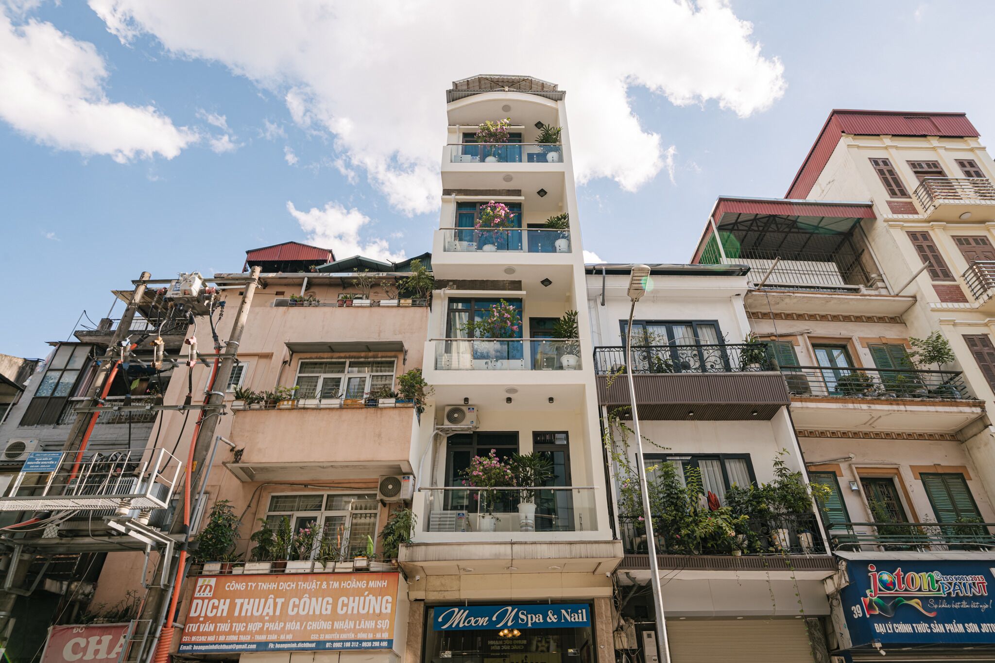 A multi-story building with balconies, a spa and nail salon on the ground floor, and various signs and advertisements.
