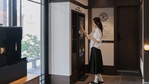 Una mujer usando un quiosco de autoservicio en el vestíbulo de un hotel, con vista al exterior.