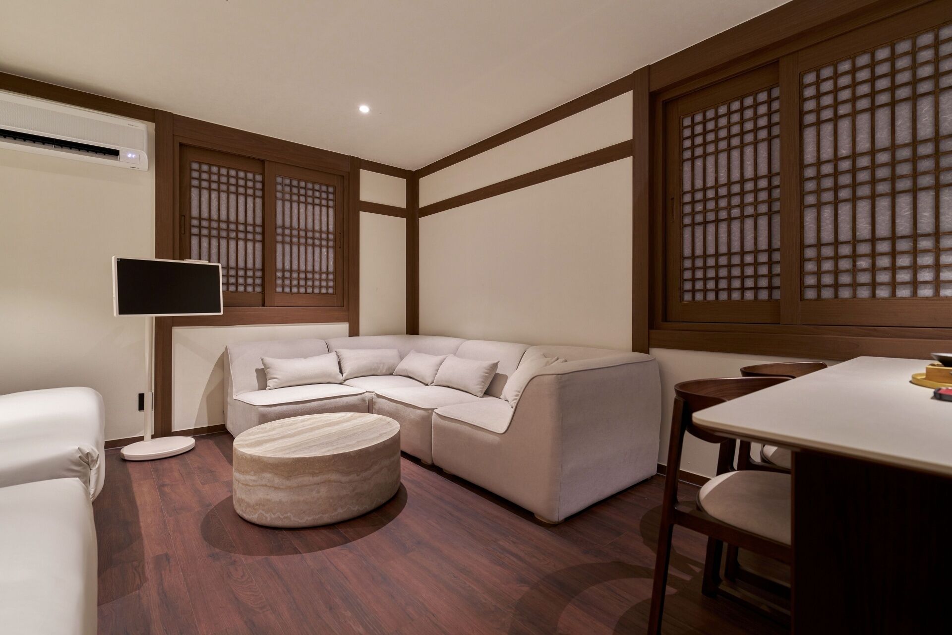 Una sala de estar moderna con un sofá modular, una mesa de centro redonda y un comedor con mesa y sillas.