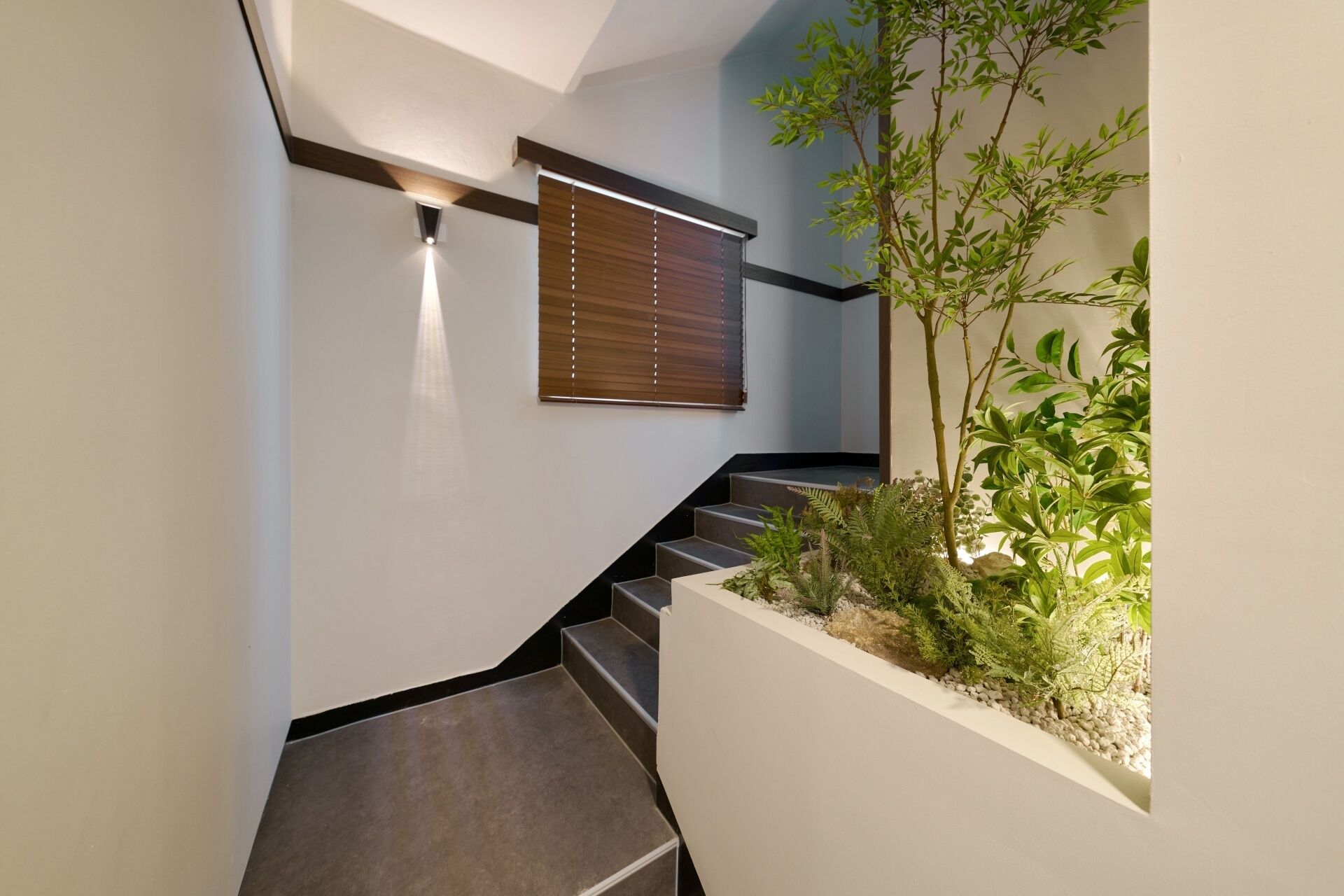 A modern staircase with a built-in planter containing various plants.