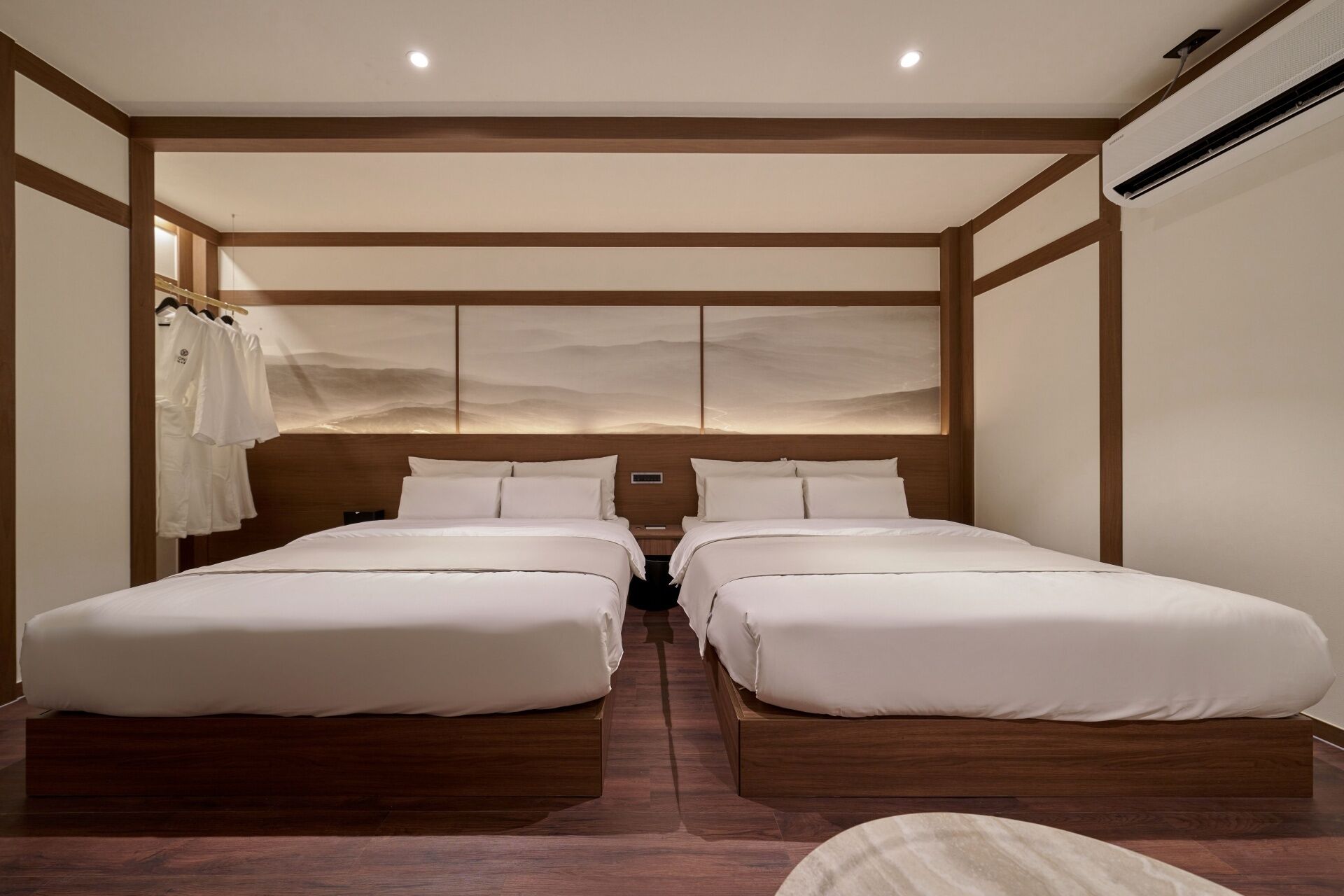 Une chambre d’hôtel avec deux lits, une tête de lit en bois et un climatiseur fixé au mur.