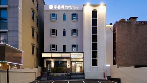 Un hotel con fachada moderna, múltiples ventanales y una entrada destacada con escalones.
