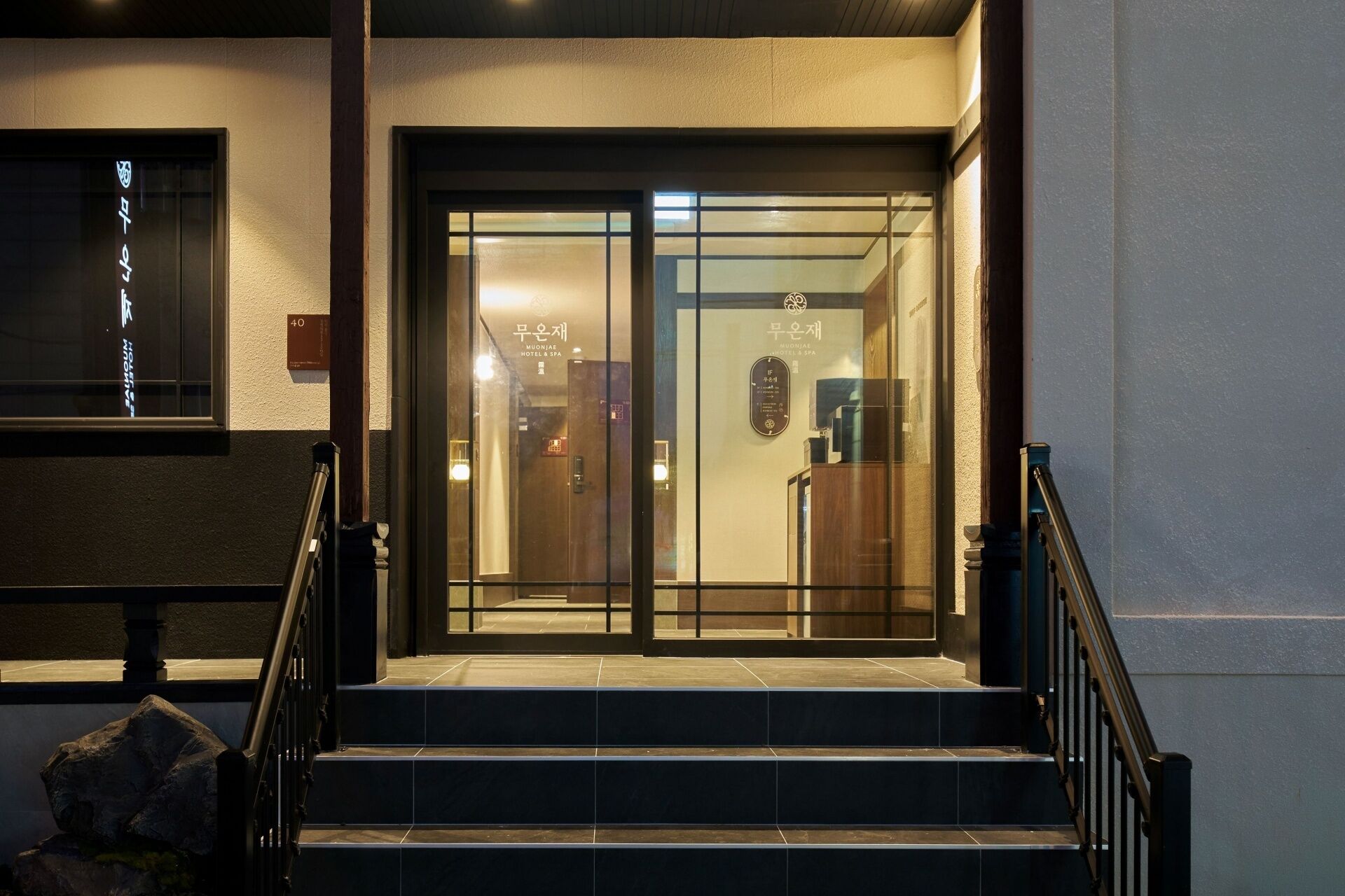 A hotel entrance with a glass door, a staircase, and a sign indicating the hotel's name.
