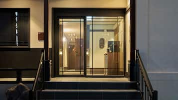 A hotel entrance with a glass door, a staircase, and a sign indicating the hotel's name.
