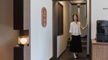 A hotel corridor with a reception desk, a sign with room numbers, and a water dispenser.