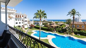 Uma área de piscina com vista para o mar, cercada por edifícios e palmeiras.