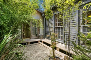 Un jardin agrémenté d’une terrasse en bois, d’un chemin de pierre et de diverses plantes.