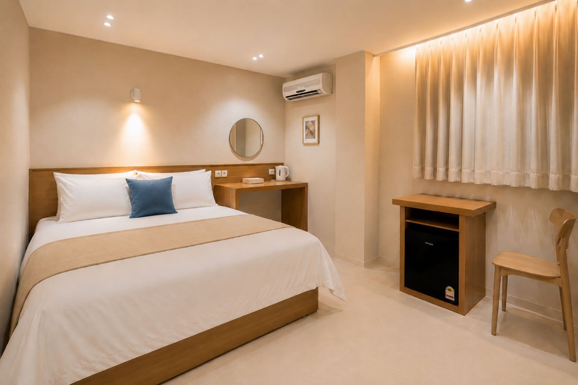 A hotel room with a bed, bedside table, a small cabinet, a chair, an air conditioning unit, and a window with curtains.