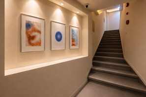 A hallway with three framed artworks on the wall and a staircase leading to another floor.