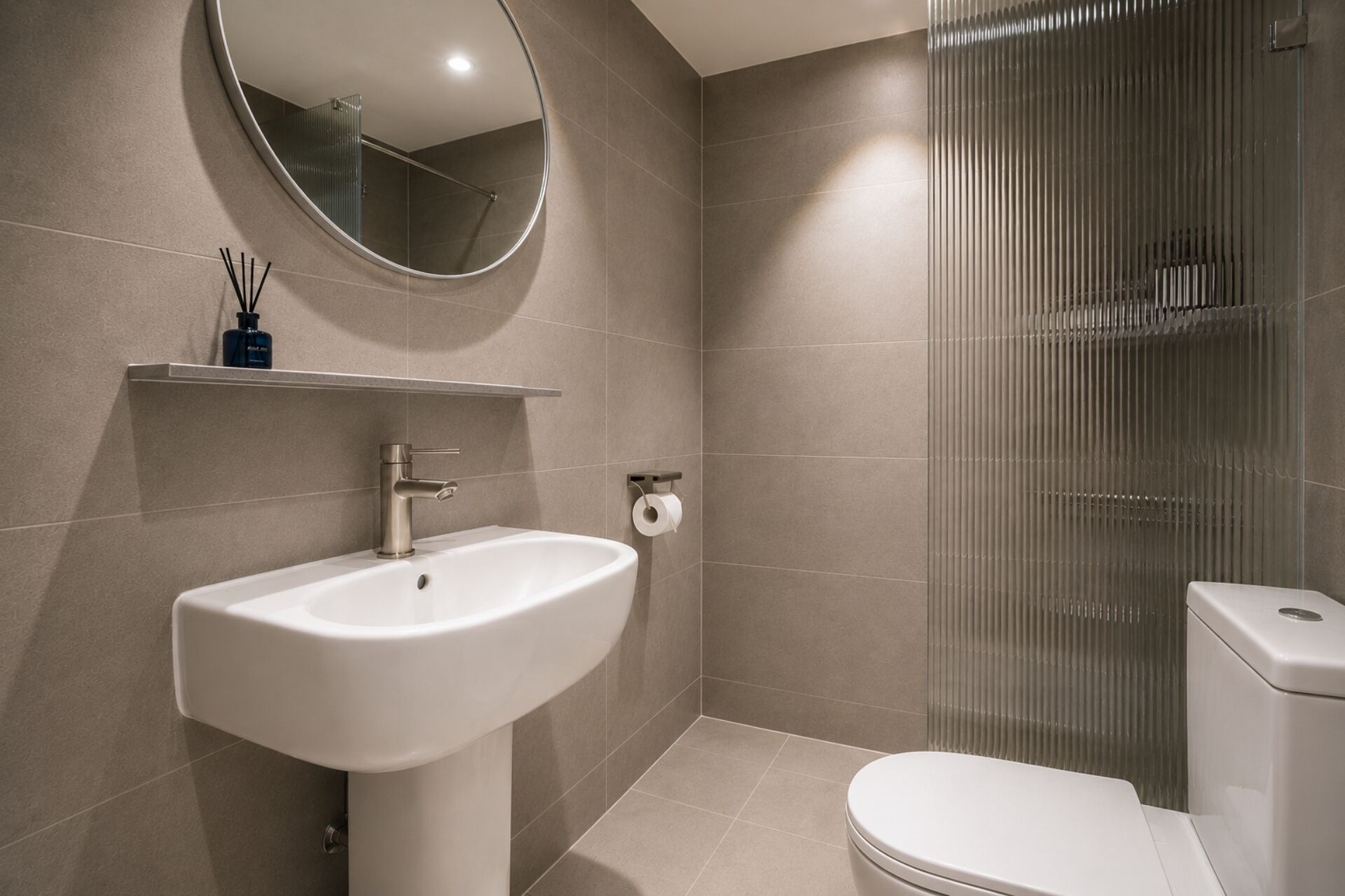 Un baño moderno con lavamanos, inodoro y cabina de ducha de vidrio.