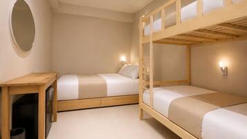 A room with bunk beds, a desk, and a trash bin.